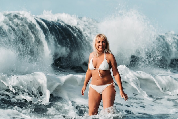 Une fille aux cheveux mouillés saute par-dessus de grosses vagues dans l'océan Atlantique, autour d'une vague avec des éclaboussures de pulvérisation et de gouttes d'eau.Tenerife.Espagne