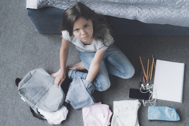 Une fille aux cheveux noirs entourée d&#39;un sac à dos gris