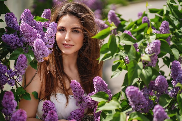 Une fille aux cheveux noirs se promène dans le jardin d'automne avec des arbres en fleurs