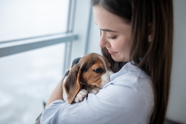 Fille aux cheveux noirs avec son chiot à la maison se sentant paisible