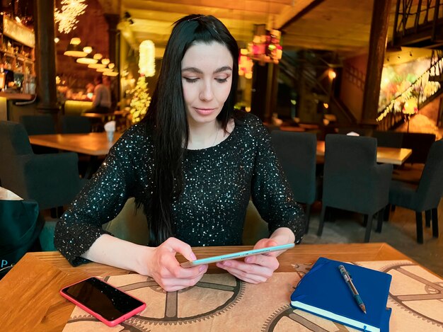 Une fille aux cheveux noirs travaille dans un café avec une tablette, un téléphone et un ordinateur portable à proximité. Coworking, organisation du workflow. Concept d'entreprise.