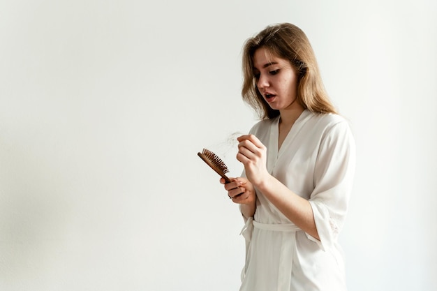 Une fille aux cheveux problématiques est assise sur le lit et les peigne fille avec un peigne est assise sur un lit en pyjama