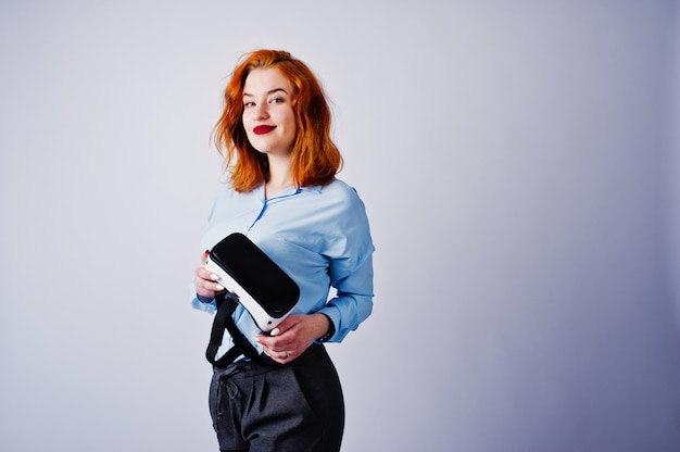 Fille aux cheveux rouge en blouse bleue avec des lunettes de vr isolé sur blanc.