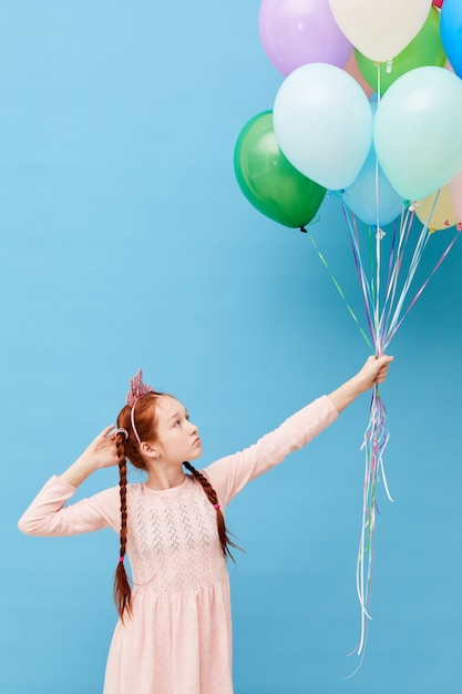 Fille aux cheveux rouges tenant des ballons