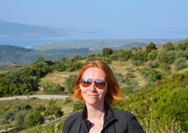 Une fille aux cheveux roux et une vue sur le pont à haubans de Rio Antirio sur le golfe de Corinthe en Grèce