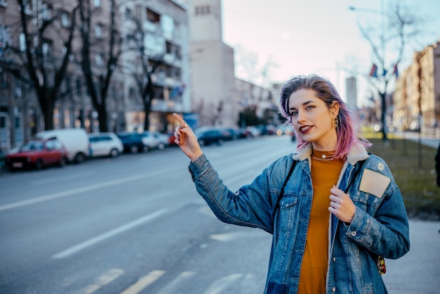 Fille aux cheveux teints héler un taxi.