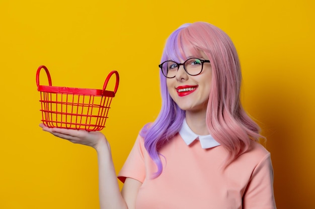 Fille aux cheveux violets et robe rose avec panier rouge sur fond jaune