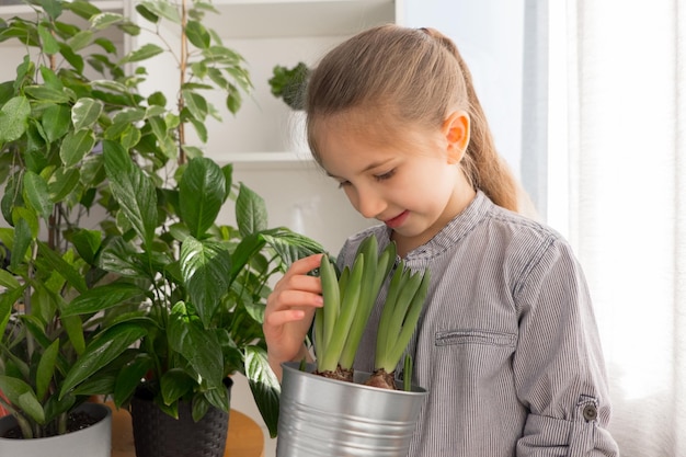 Une fille aux longs cheveux blonds vêtue d'une chemise regarde et admire un concept de jardin fleuri