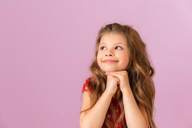 Une fille aux longs cheveux bouclés, en train de rêver.