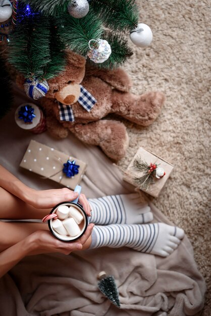 Fille aux longues jambes près de l'arbre de Noël avec des cadeaux