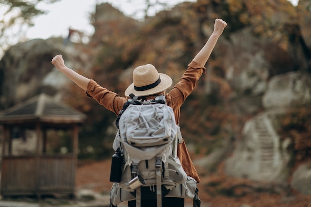 Fille aux mains levées se détendre au sommet de la montagne, regardant le magnifique paysage d'automne