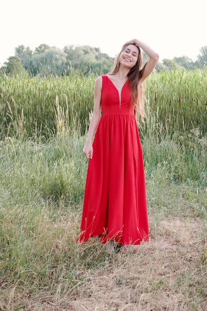 Fille aux pieds nus aux cheveux bruns aux cheveux longs en robe rouge sur la côte de la rivière.