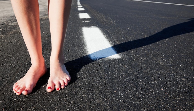 Fille aux pieds nus sur la route.