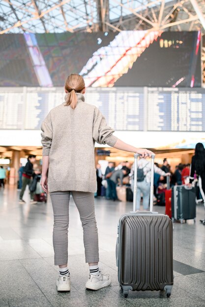 Fille avec des bagages attend le départ.