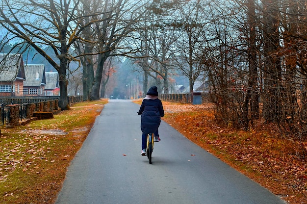 Fille sur des balades à vélo dans le village brumeux d'automne