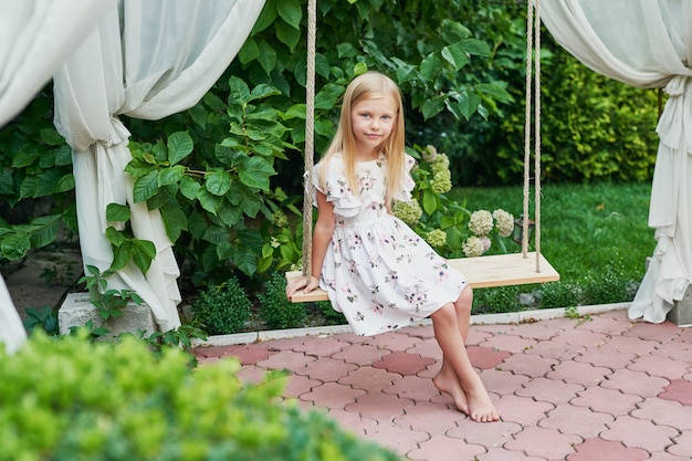 fille sur une balançoire en été dans le jardin