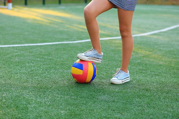 Fille avec un ballon dans ses mains sur le terrain de football.