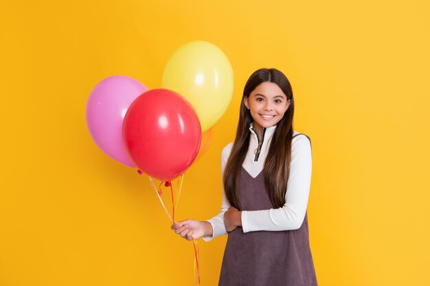 Fille avec des ballons colorés de fête sur fond jaune
