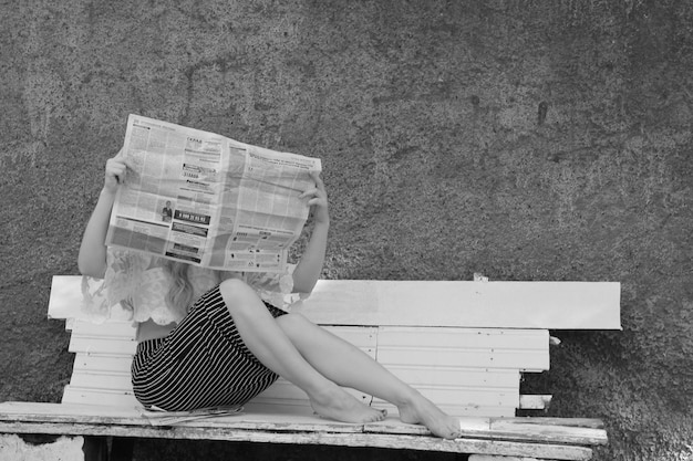 Photo une fille sur un banc avec un journal.