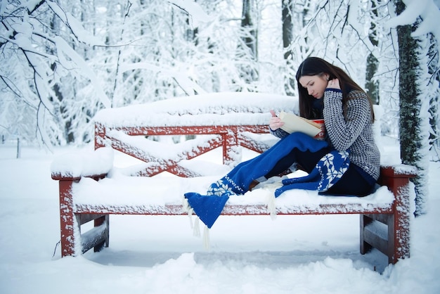 Une fille sur un banc de parc de neige.