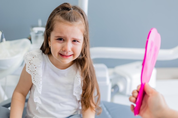 Une fille avec un bandage rose regarde la main d'un médecin