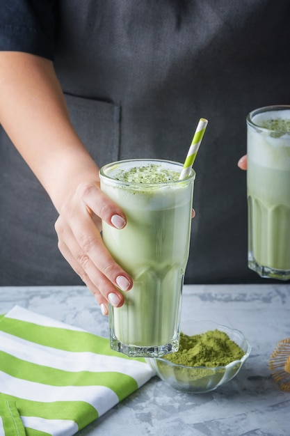 Fille Barista tend un verre avec une boisson saine. Latte à base de thé vert matcha