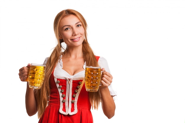 Fille bavaroise heureuse souriant à la caméra, tenant des chopes de bière. Jolie femme allemande en robe traditionnelle Oktoberfest servant bières, espace copie