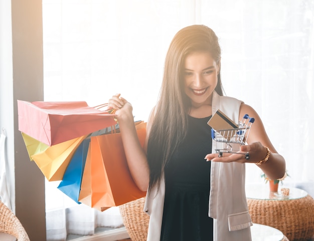 Fille de beau sourire tenant le sac à provisions coloré