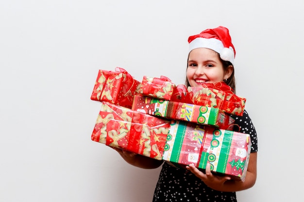 Fille avec beaucoup de cadeaux et chapeau de Noël, fond blanc