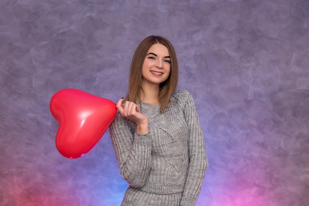 Fille de beauté avec ballon à air en forme de coeur rouge tourné en studio