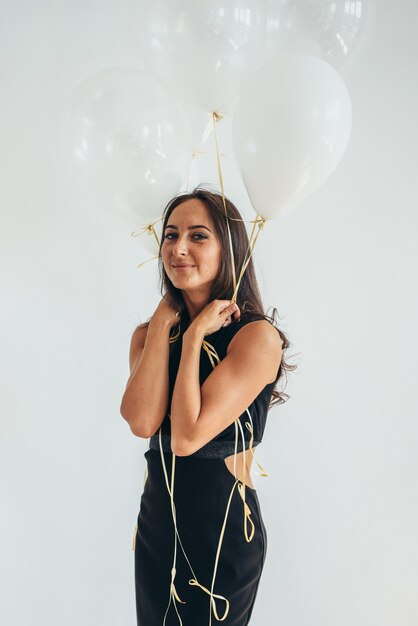 Fille de beauté avec des ballons à air souriant célébrant les vacances.