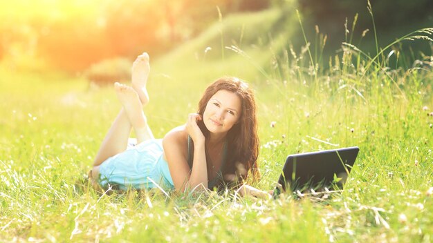 Fille de beauté avec ordinateur portable à l'extérieur dans un parc par temps ensoleillé