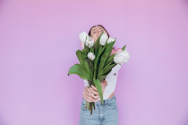 Fille de beauté tenant le bouquet de fleurs de tulipes de printemps et souriant. La Saint-Valentin. Fête des mères.