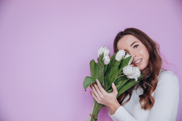 Fille de beauté tenant le bouquet de fleurs de tulipes de printemps et souriant. La Saint-Valentin. Fête des mères.