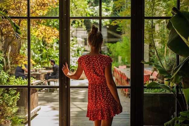 Photo fille en belle robe rouge en regardant la fenêtre