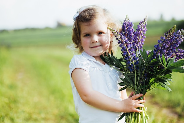 Fille avec de belles fleurs bleues sur une soirée d'été ensoleillée.