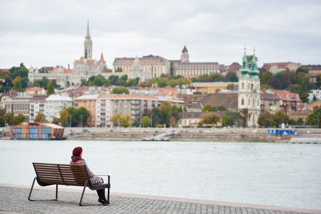 Fille en béret rouge est assise sur un banc