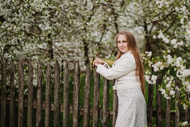 une fille en blanc dans un jardin fleuri des fleurs de cerisier une fille aux cheveux longs jeune fille