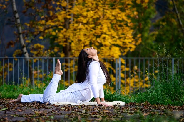 Fille en blanc en position de yoga dans le parc