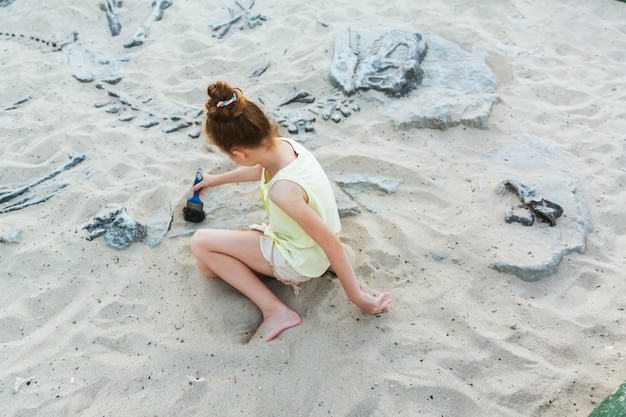 Fille blanche s&#39;amuser à creuser dans le sable au parc d&#39;aventure, mise au point sélective