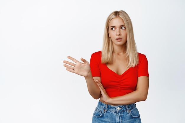 Fille blonde agacée en agitant la main et rouler les yeux étant irrité debout sur fond blanc