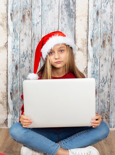 Fille blonde à l'aide d'un ordinateur portable à Noël pour communiquer