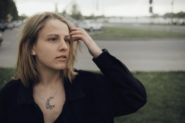 Une fille blonde ajuste ses cheveux et regarde au loin