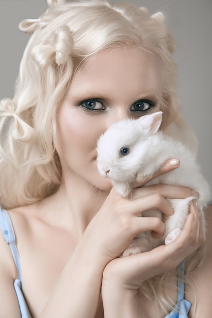 Fille blonde albinos en robe élégante posant avec mignon petit lapin