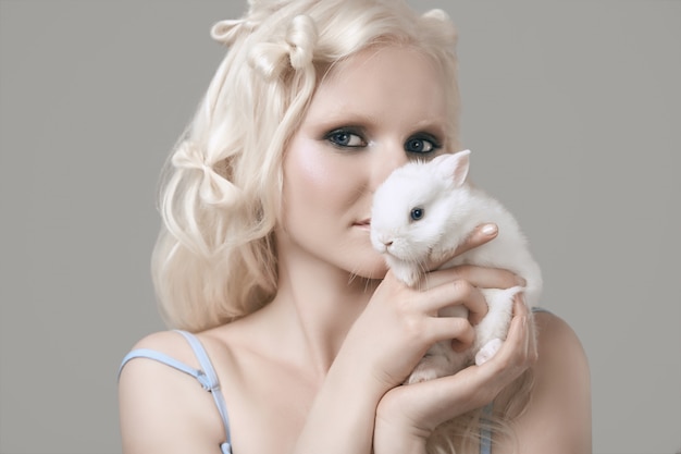 Fille blonde albinos en robe élégante posant avec mignon petit lapin