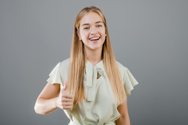 Fille Blonde Assez Heureuse Montrant Les Pouces Vers Le Haut Isolé Sur Gris