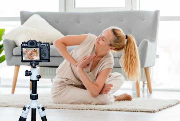 Fille blonde assise dans le yoga asana sur le sol dans la chambre avec la lumière du soleil