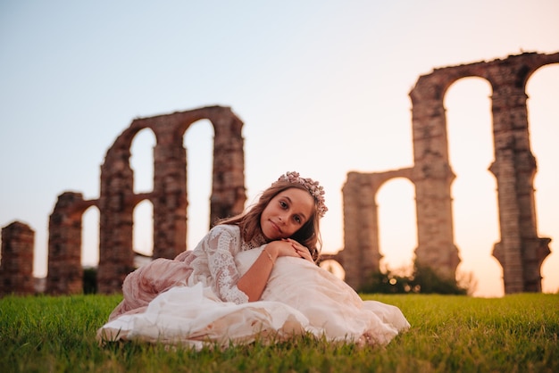 Fille blonde aux cheveux bouclés vêtue d'une robe de communion à Merida