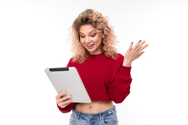 Fille blonde bouclée surprise européenne avec sur tablette sur fond blanc.