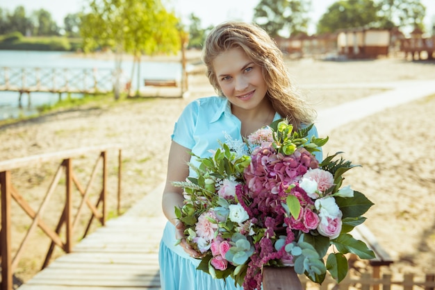 Fille blonde avec bouquet dans une robe bleue